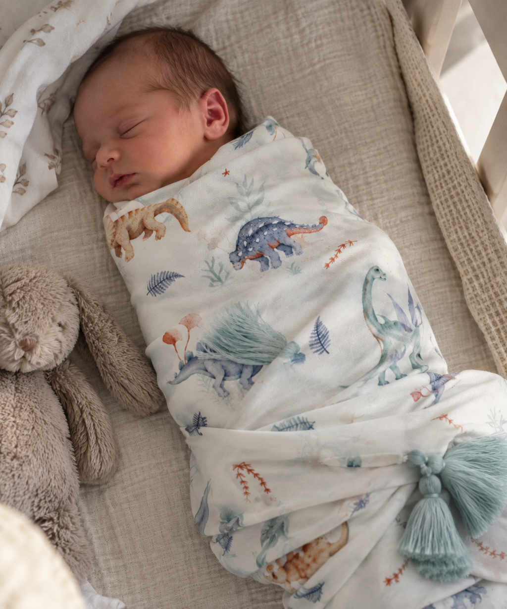 Swaddle Dinosauri in viscosa di bambù con nappine verde acqua in ambiente naturale
