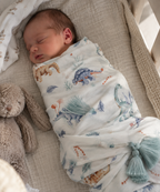 Swaddle Dinosauri in viscosa di bambù con nappine verde acqua in ambiente naturale
